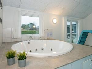 エーベルトフトにある18 person holiday home in Ebeltoftの窓付きのバスルーム(大きな白いバスタブ付)