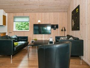 een woonkamer met zwarte lederen meubels en een televisie bij 18 person holiday home in Ebeltoft in Ebeltoft
