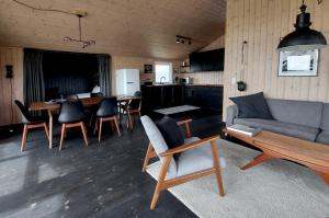 a living room with a couch and a table and chairs at Hilltop Cabin Hekla - Golden Circle - Geysir - Mountain View in Reykholt