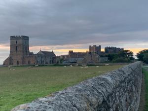 a stone wall in a field with a castle at Brada View Bamburgh in Bamburgh