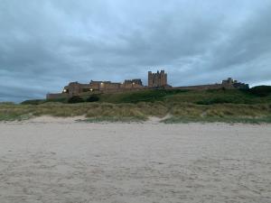 a castle sitting on top of a hill next to a beach at Brada View Bamburgh in Bamburgh