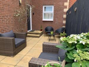 a patio with wicker chairs and a brick wall at Brada View Bamburgh in Bamburgh