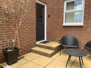a patio with a black door and a chair and a plant at Brada View Bamburgh in Bamburgh
