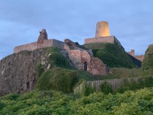 a castle on a hill with a fence at Brada View Bamburgh in Bamburgh