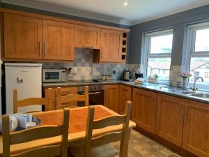 a kitchen with wooden cabinets and a wooden dining table at Brada View Bamburgh in Bamburgh