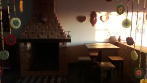 a room with a fireplace and a table and a window at Poente Guest House in Conceição da Ibitipoca