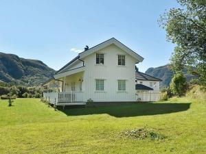 a white house in a field with mountains in the background at 8 person holiday home in Oksvoll in Oksvoll
