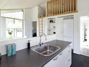 uma cozinha com um lavatório de aço inoxidável e armários brancos em 8 person holiday home in Haderslev em Årøsund