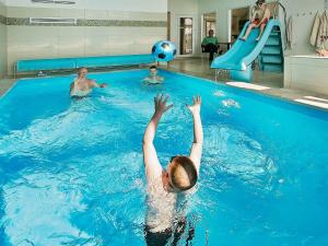 18 person holiday home in Bogense في بوجنسي: بنت في مسبح ويدها في الماء