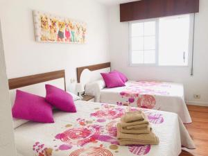 two beds in a room with pink and white at Enjoy Sanxenxo,200m Playa, Balcón Vistas Cíes, Piscina & Terraza Azotea,2 plazas Garaje, 2 Baños, Muy Luminoso, Muy Tranquilo,Muy Equipado, Céntrico in Sanxenxo +20 photos
