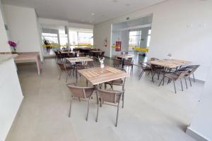 une salle à manger avec tables, chaises et fenêtres dans l'établissement 304 Flat Edifício Everest, à Caldas Novas