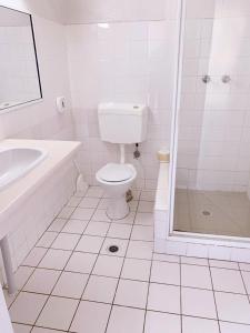 a white bathroom with a toilet and a shower at Walgett Motel in Walgett