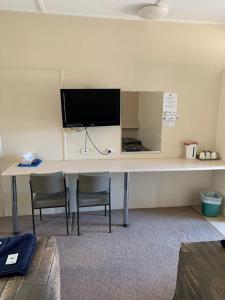 a desk with two chairs and a television on a wall at Walgett Motel in Walgett