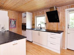 una cucina con armadi bianchi e piano di lavoro nero di 6 person holiday home in L kken a Grønhøj