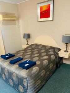 a hotel room with a bed with blue towels on it at Walgett Motel in Walgett
