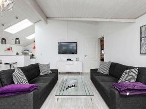 sala de estar con sofá negro y TV en Three-Bedroom Holiday home in Blokhus 17, en Blokhus