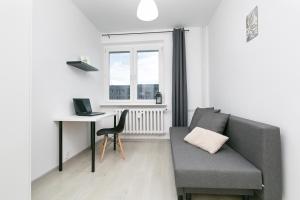 a living room with a couch and a desk and a window at Rooms4Less in Gdańsk