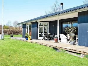 une maison avec une terrasse en bois dans la cour dans l'établissement 6 person holiday home in Odder, à Norsminde