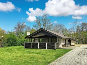 a small cabin with a roof on a grass field at Three-Bedroom Holiday home in Hemmet 67 in Falen