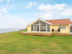 a small yellow house on a hill with the ocean at 4 person holiday home in Vinderup in Vinderup