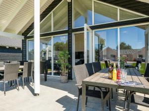 a patio with a wooden table and chairs and glass windows at 16 person holiday home in Hasselberg in Kappeln