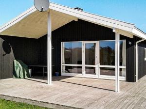 a patio with a white roof and a wooden deck at 6 person holiday home in Harbo re in Harboør