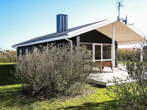 a small black house with a porch and a bench at 6 person holiday home in Harbo re in Harboør