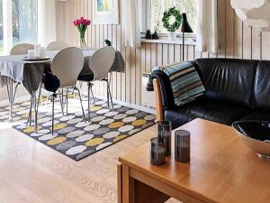 a living room with a black leather couch and a table at 4 person holiday home in L s in Læsø