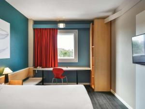 a room with a bed and a desk and a window at Ibis Madrid Getafe in Getafe