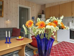 eine blaue Vase voller orangefarbener und weißer Blumen auf dem Tisch in der Unterkunft 4 person holiday home in Vejers Strand in Vejers Strand