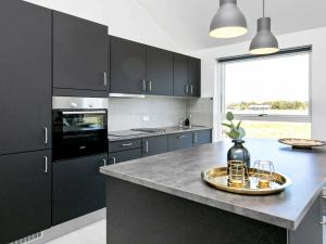 a kitchen with black cabinets and a large window at 6 person holiday home in L kken in Løkken