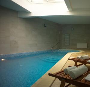 a large swimming pool with blue water in a building at Hotel Carpați in Predeal