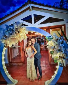 a bride and groom standing under an arch with flowers at HOTEL BOUTIQUE EL FARO BY AROMAX in Medellín