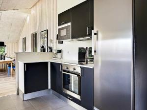 a kitchen with black and white cabinets and a refrigerator at 14 person holiday home in Stege in Stege