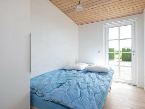 - une chambre avec un lit doté d'une couette bleue et d'une fenêtre dans l'établissement 6 person holiday home in Faaborg, à Fåborg