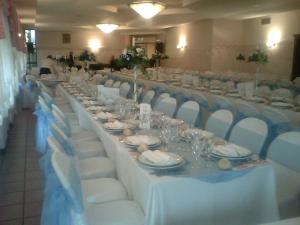 długi stół z białymi krzesłami, talerzami i okularami w obiekcie Hotel Sanvitale w mieście Fontanellato