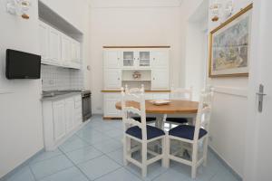 una cocina con armarios blancos y una mesa y sillas de madera. en Un Angolo di Mare...nel centro di Ischia!, en Isquia