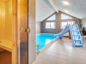 a swimming pool with a slide in a room with a house at 20 person holiday home in Grenaa in Grenå