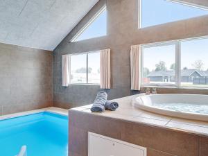 a large bathroom with a tub and a swimming pool at 20 person holiday home in Grenaa in Grenå