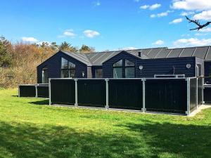 a black house with a fence in front of it at Three-Bedroom Holiday home in Tarm 12 in Hemmet