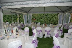uma tenda montada para um casamento com mesas brancas e arcos roxos em Hotel Sanvitale em Fontanellato