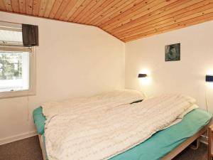 a bed in a bedroom with a wooden ceiling at 6 person holiday home in R m in Bolilmark