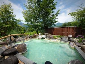 藏王溫泉的住宿－昭四季酒店，一个带岩石的花园内的热水浴池