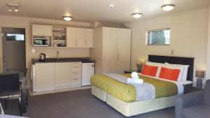 a bedroom with a large bed and a kitchen at Delago Motel/Apartments in Christchurch