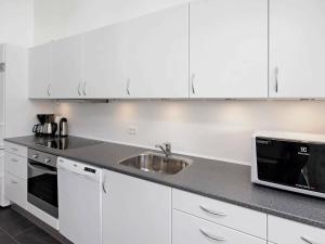a white kitchen with a sink and a microwave at 8 person holiday home in R m in Rømø Kirkeby