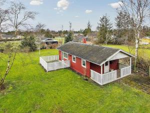una pequeña casa roja en un campo de hierba en Holiday home Storvorde III, en Storvorde