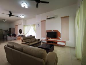 sala de estar con sofá y TV de pantalla plana en Venn Homestay, Balik Pulau, en Balik Pulau