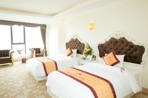 two beds in a hotel room with white at Lao Cai Royal Hotel in Lao Cai