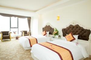 a hotel room with two beds and two chairs at Lao Cai Royal Hotel in Lao Cai