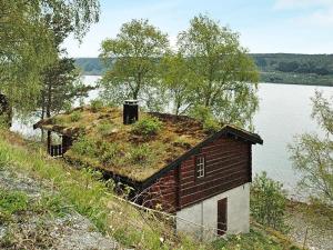 an old house with grass on the roof next to a lake at Two-Bedroom Holiday home in Surna in Glerem